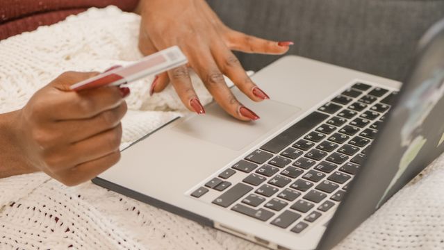 person using a laptop while holding a credit card